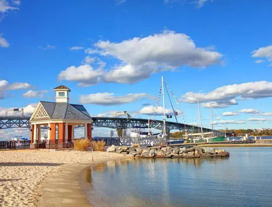 Harbor with boats and a small building under a bright blue sky.