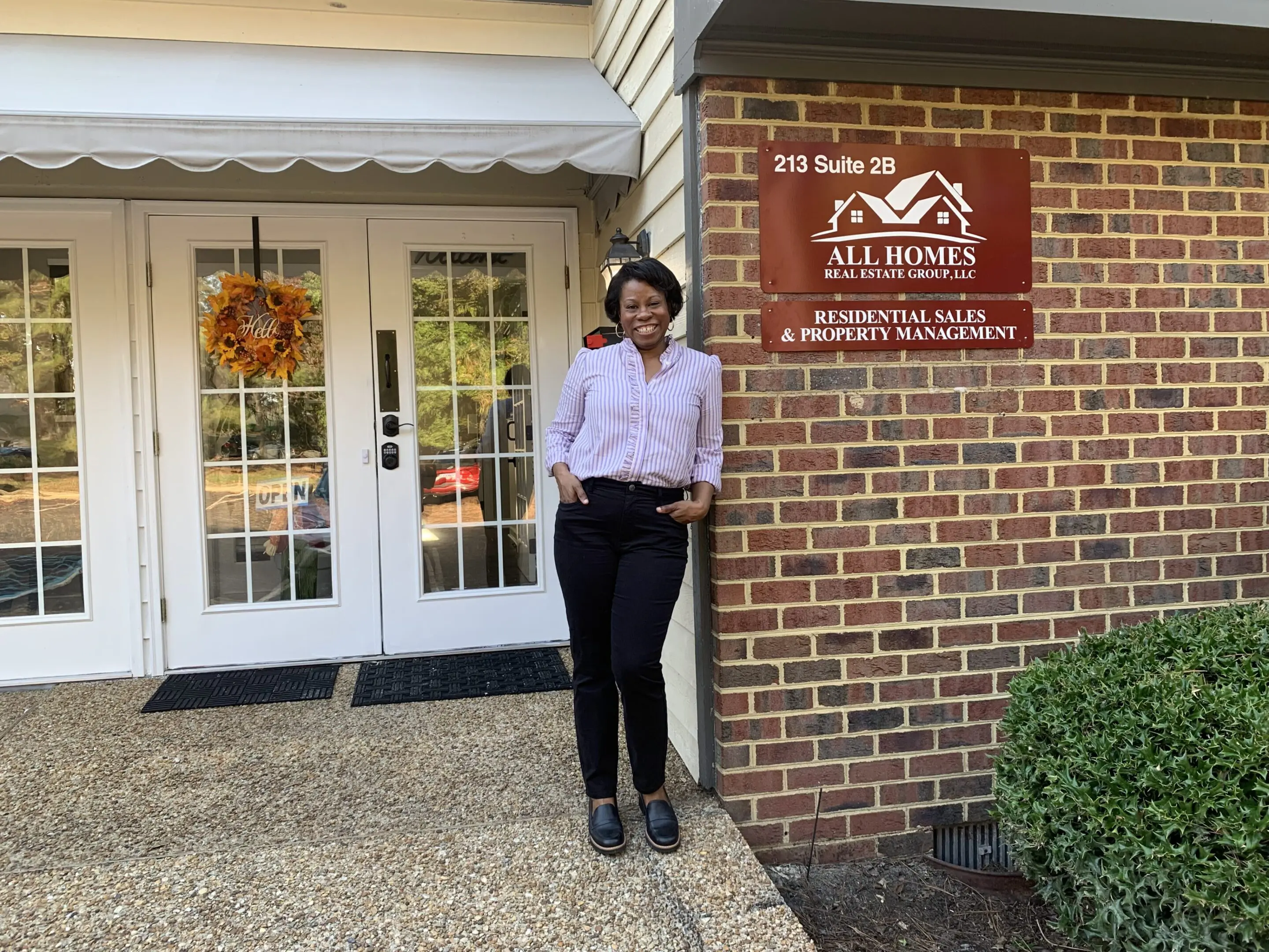 Person standing outside a brick building with a sign.