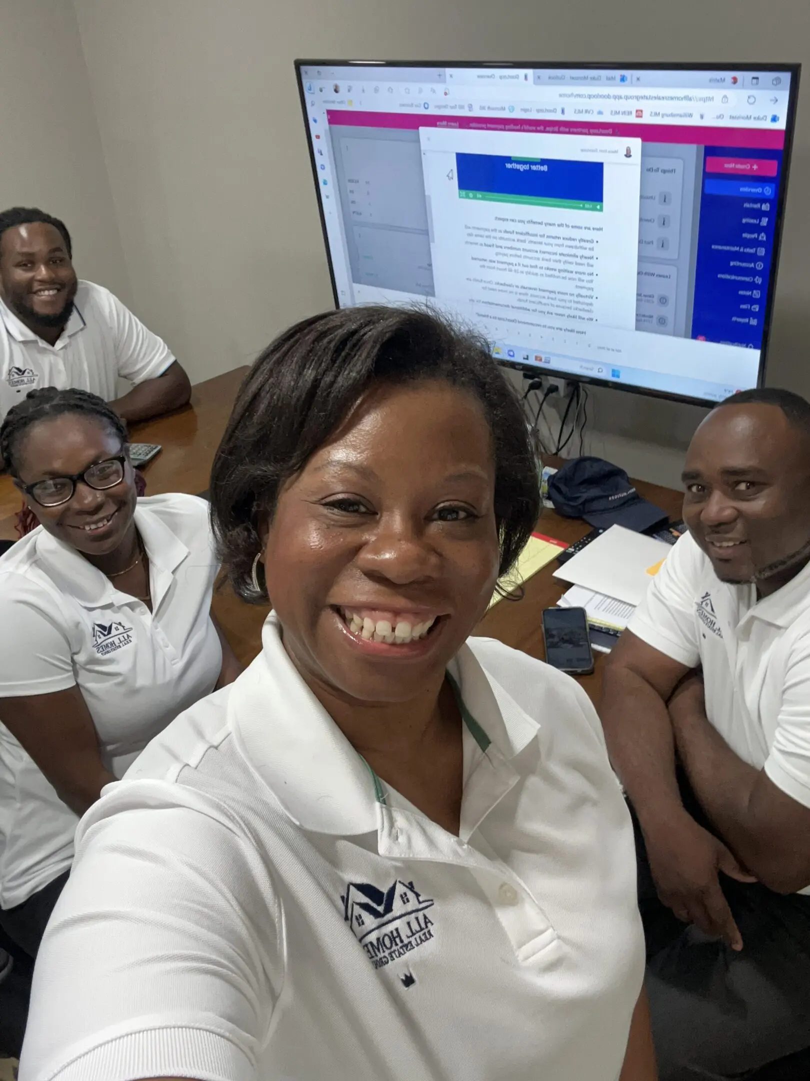 Four colleagues smiling together in an office setting.
