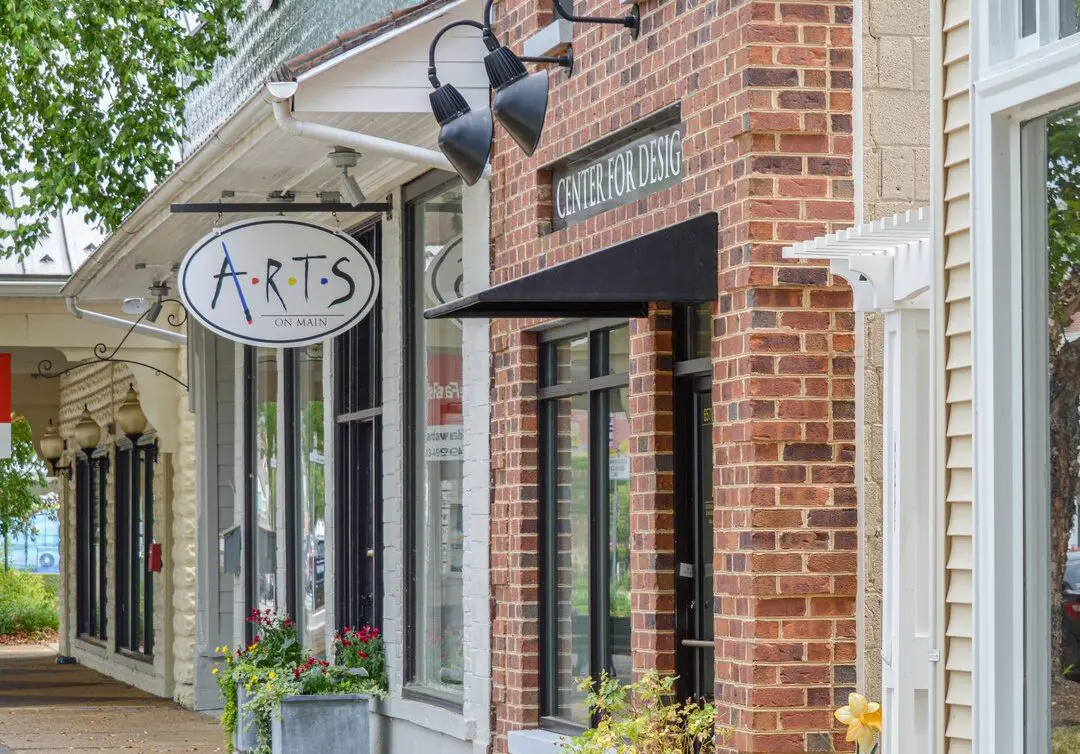 A charming brick storefront with an arts sign hanging outside.