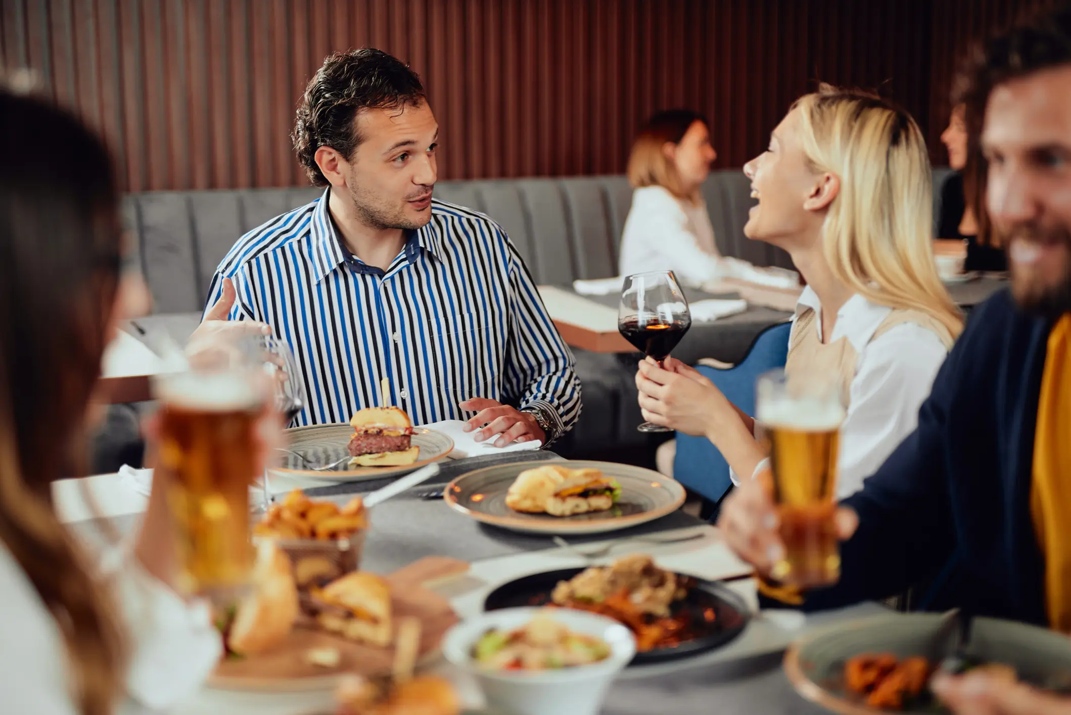 Two people engaged in a lively conversation over a meal at a restaurant.