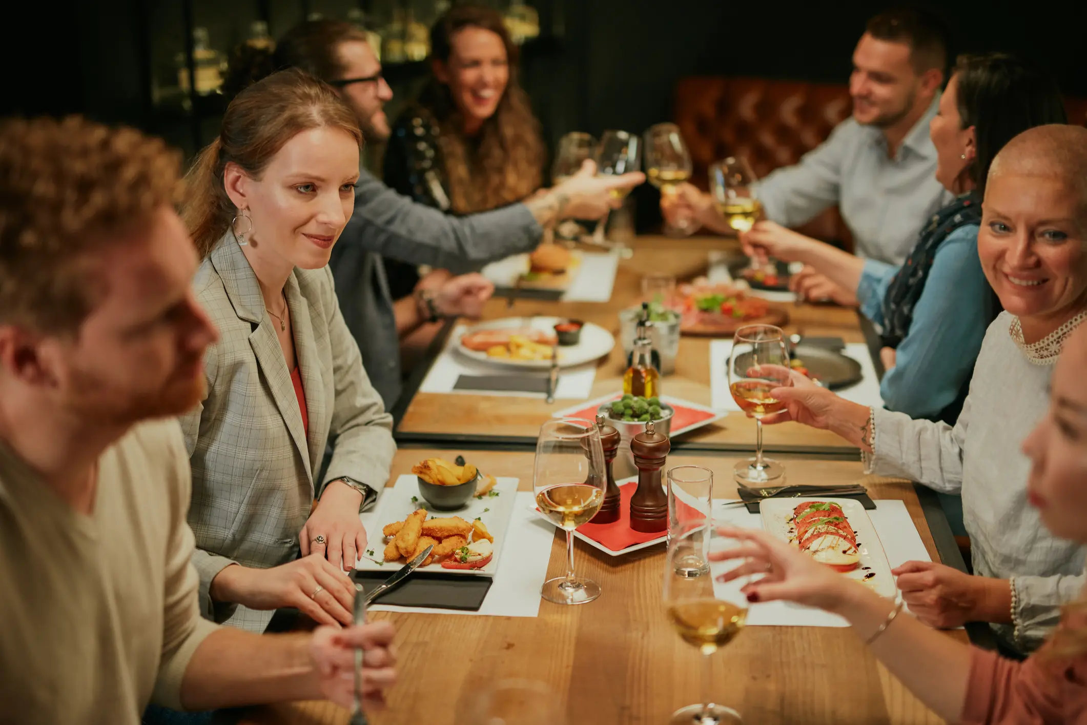 People enjoying a meal and drinks together at a lively restaurant table.