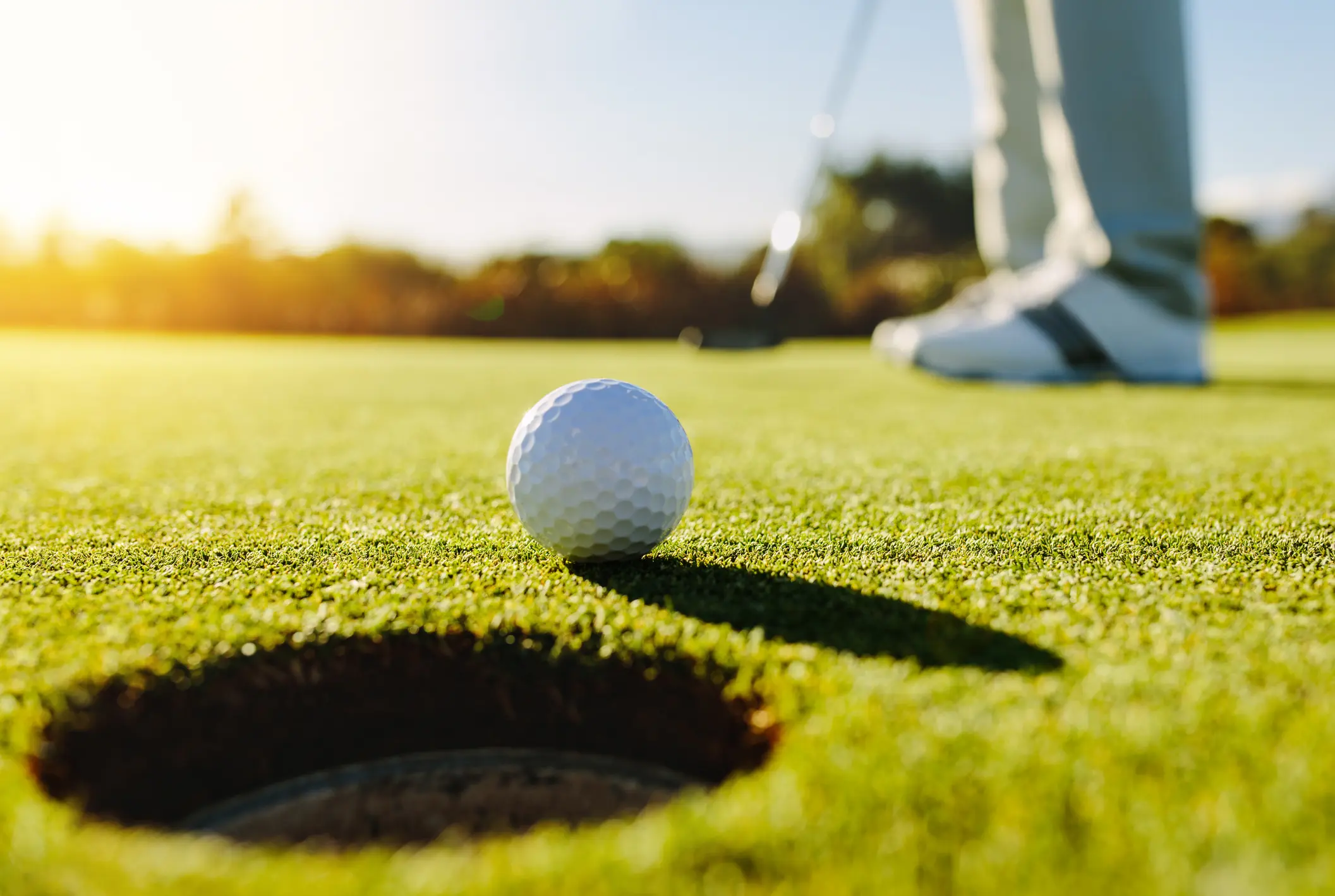 Golf ball near the hole on a green putting surface.