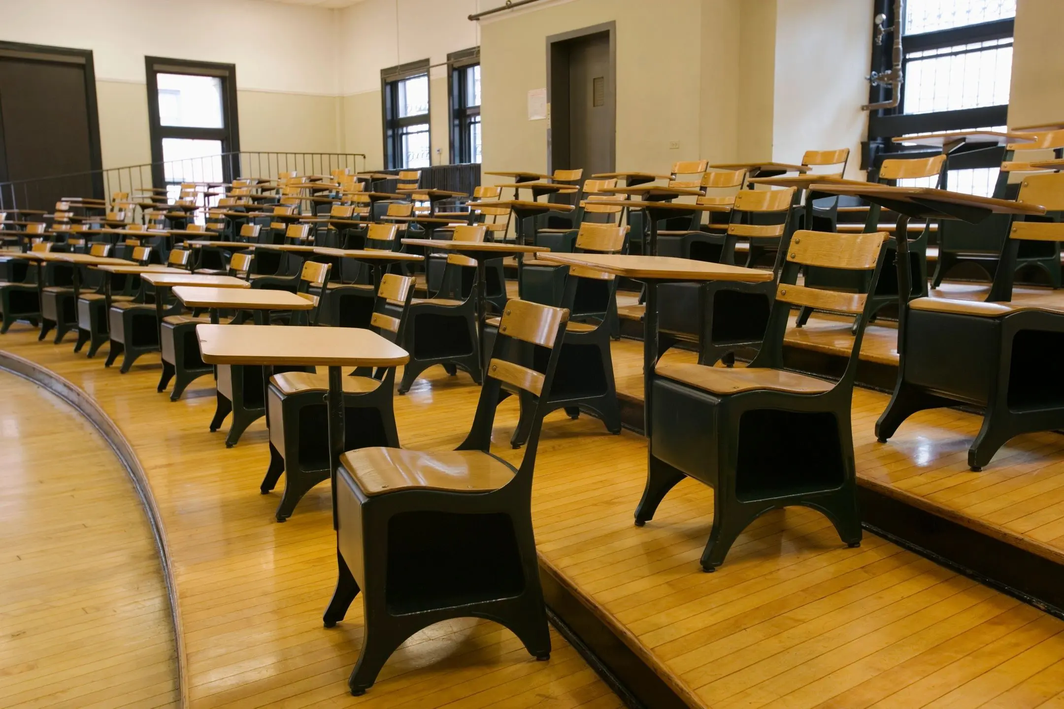 Empty classroom with wooden desks and chairs.