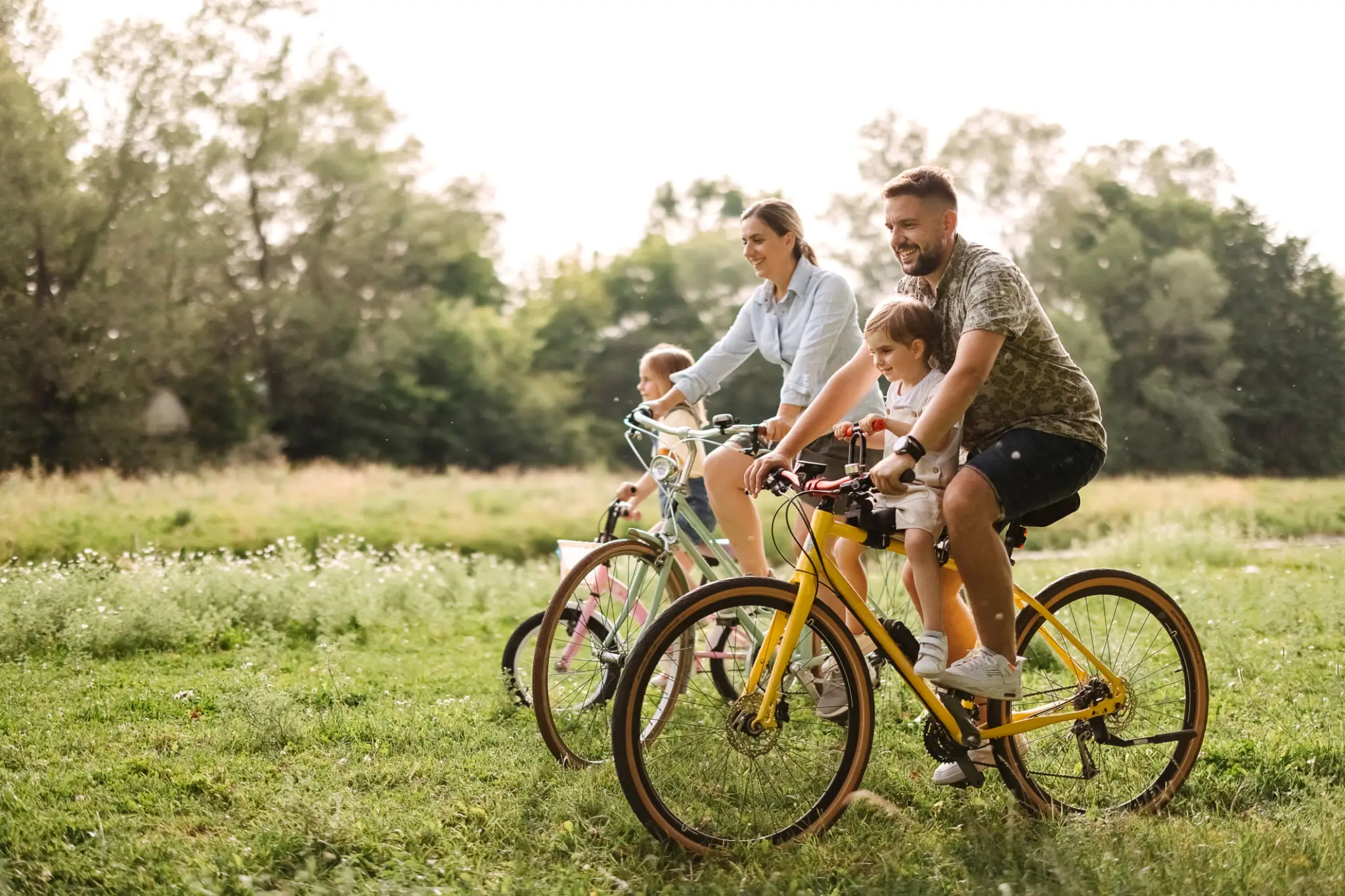 Family enjoying a bike ride together in a sunny park.