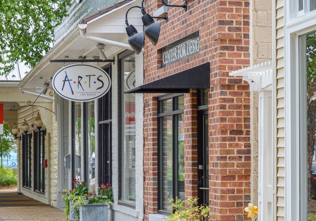 A charming brick storefront with an arts sign hanging outside.