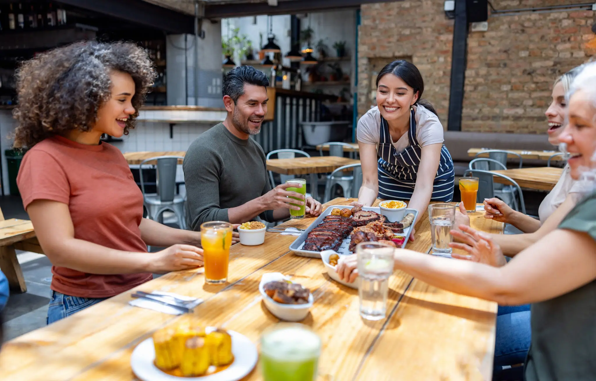 Friends enjoying a meal and drinks together at a cozy outdoor table.